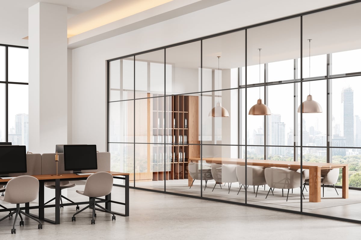 Contemporary office interior with shared desks and a glass-enclosed meeting room.